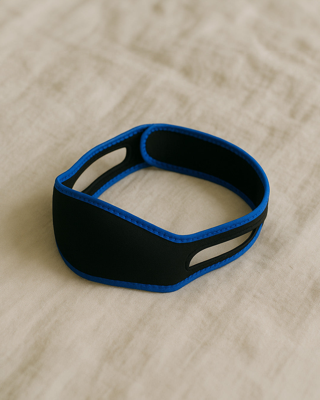 Black and blue chin strap on a cream linen sheet