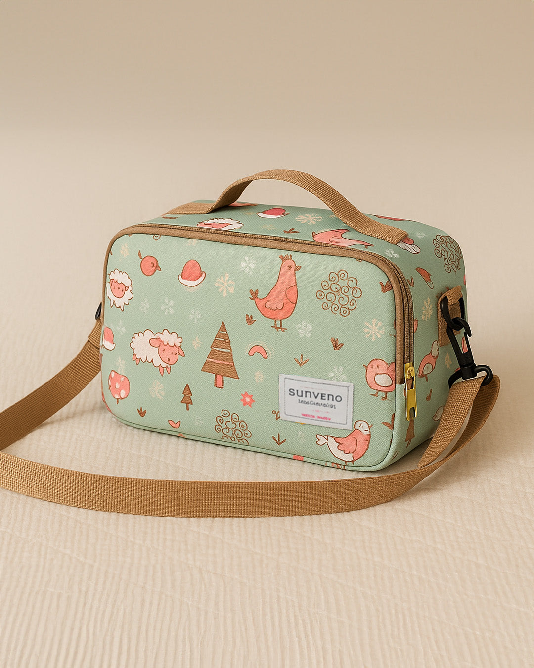 Light green baby diaper bag with animal pattern and brown strap on beige background