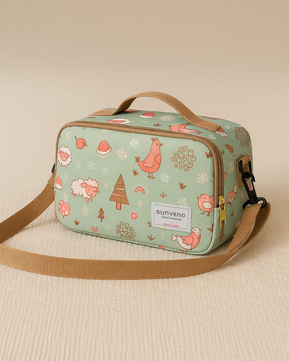 Light green baby diaper bag with animal pattern and brown strap on beige background