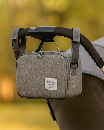 Grey baby diaper bag attached to a stroller with a blurred natural background