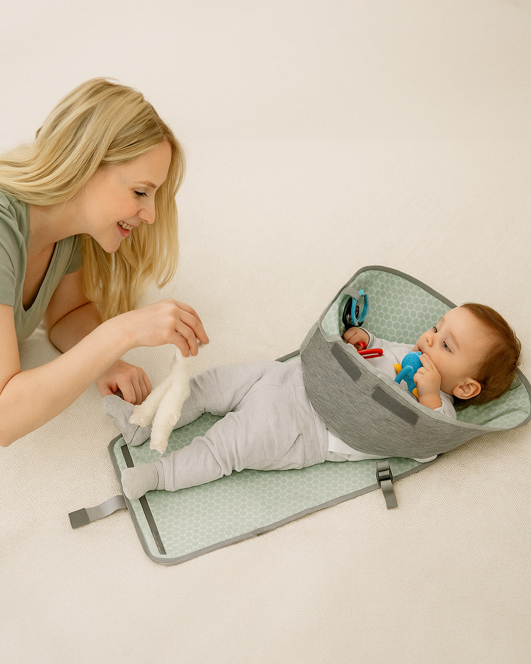 Mother about to change baby's diaper on a green and gray change mat.