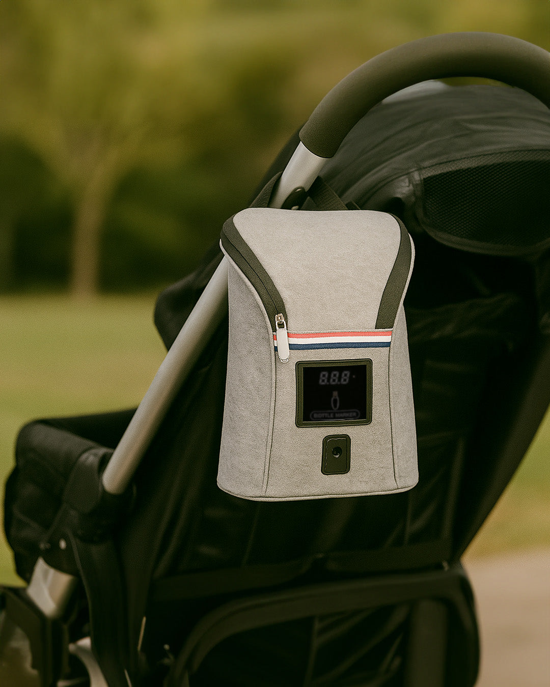 Bottle warmer with digital display attached to a stroller in an outdoor setting