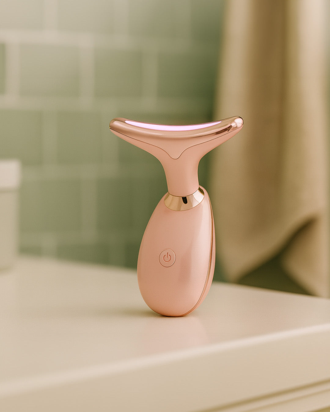 Rose gold thermal facial massager on a bathroom counter with blurred background