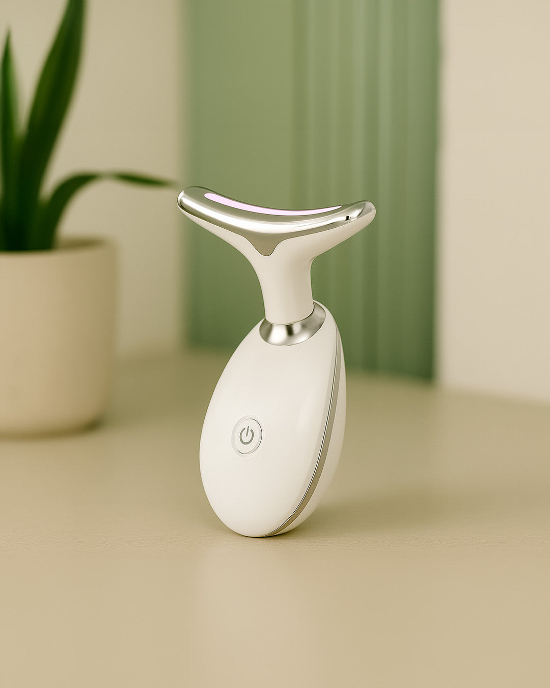 White thermal facial massager on a beige surface with a green plant in the background