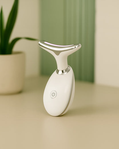 White thermal facial massager on a beige surface with a green plant in the background