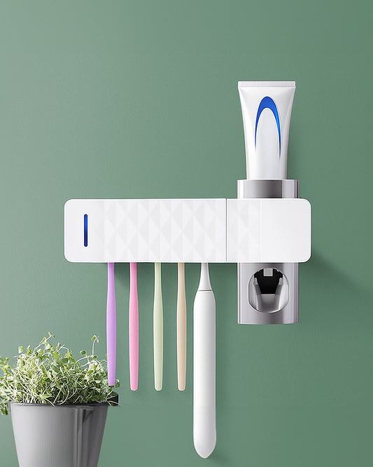Automatic toothbrush steriliser mounted to a sage bathroom wall holding multiple toothbrushes and toothpaste