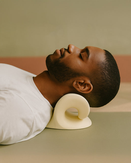 Person lying down with a white massage pillow on a neutral background