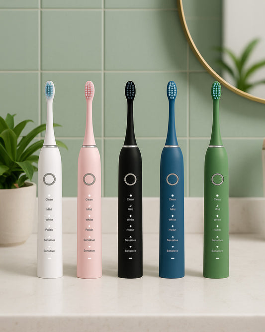 Five different coloured electric sonic toothbrushes sitting on a light bathroom stone counter with sage tiles and mirror