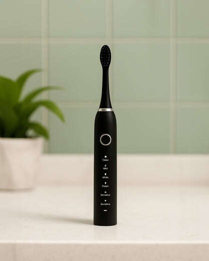 Black electric toothbrush on a bathroom counter with a green tiled wall in the background