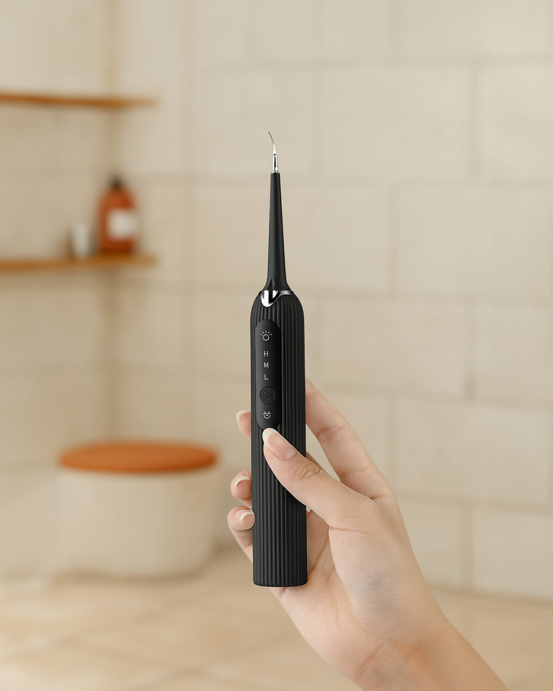 Hand holding a black electric toothbrush against a neutral background
