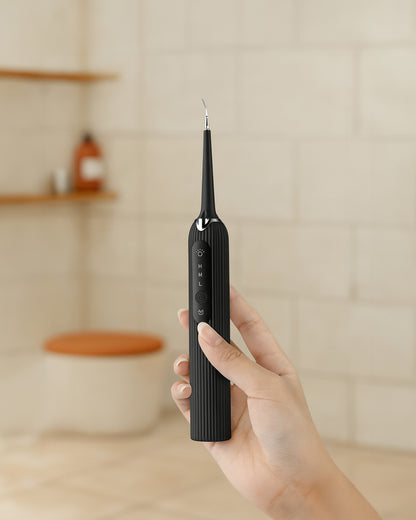 Hand holding a black electric toothbrush against a neutral background