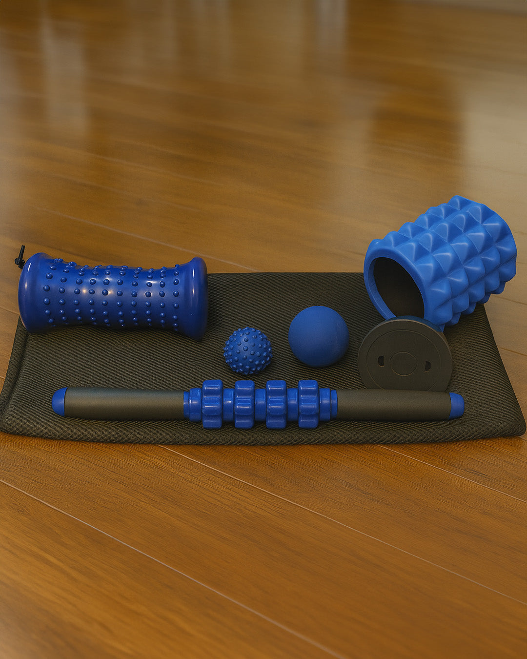 Foam roller set with massage ball on a mat on a wooden floor