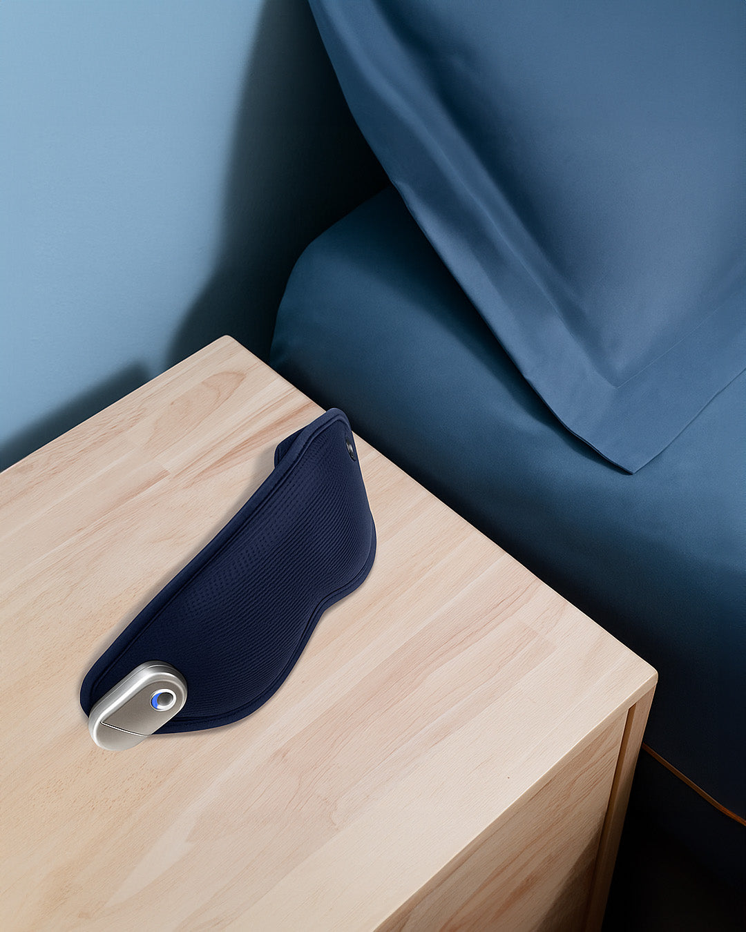Navy blue pillow on a wooden side table against a blue wall.